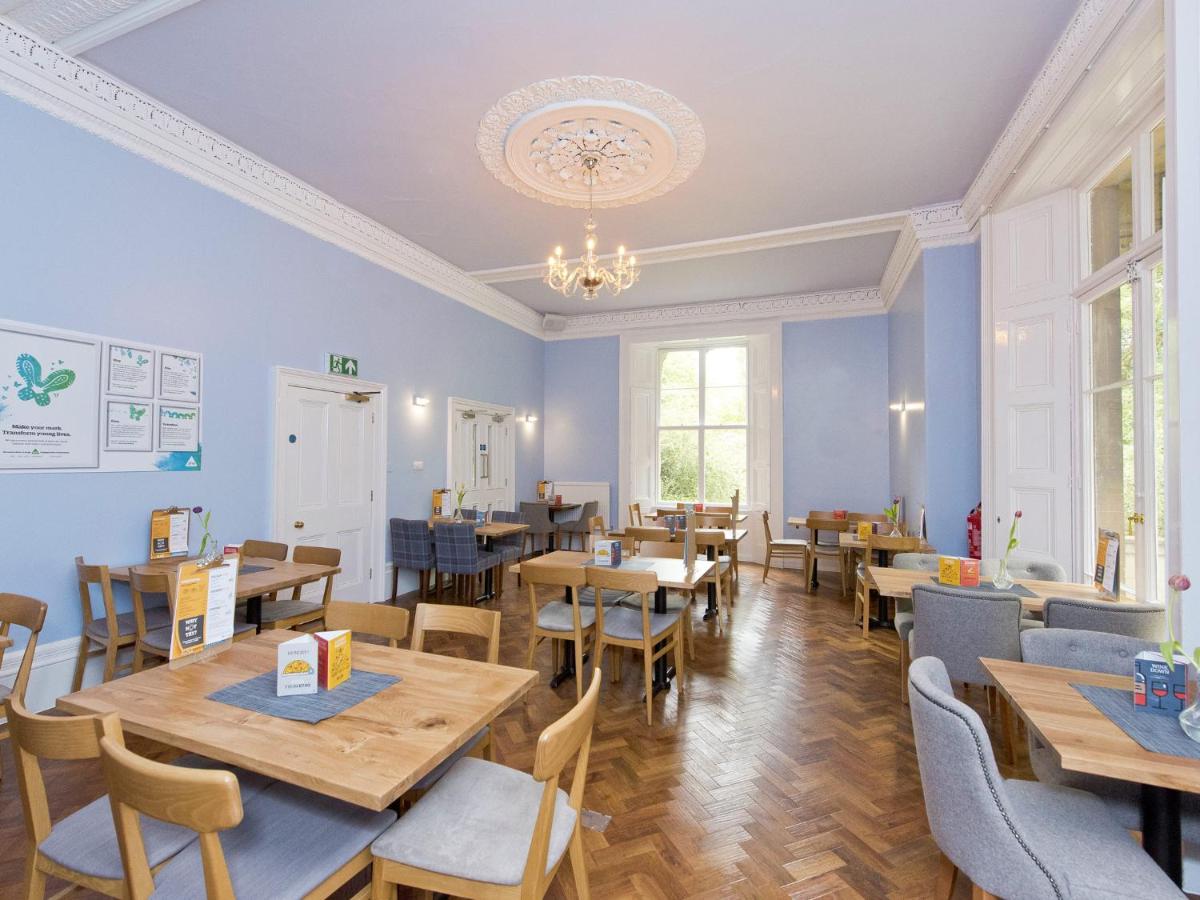 a restaurant with tables and chairs and a chandelier at YHA Bath in Bath