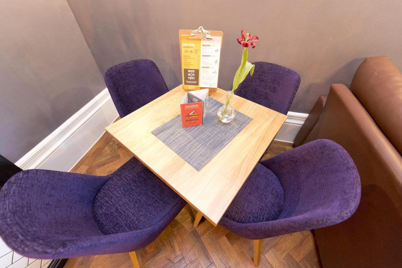 a table with purple chairs and a vase of flowers at YHA Bath in Bath
