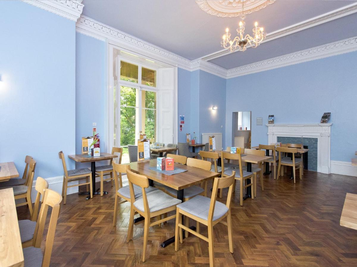 a dining room with blue walls and wooden tables and chairs at YHA Bath in Bath